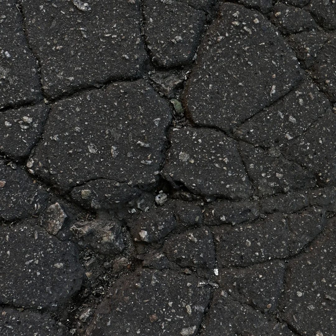 Close-up of severely cracked asphalt pavement with a network of fatigue cracks.